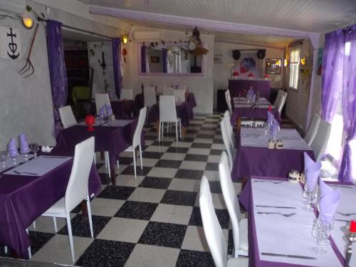 a restaurant with purple tables and chairs and a checkered floor at auberge des garrigues in Nîmes