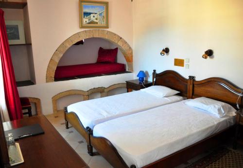 1 dormitorio con 2 camas, mesa y espejo en Margarita Hotel en Kýthira