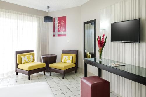a waiting room with two chairs and a table and a tv at Mercure Nadi in Nadi
