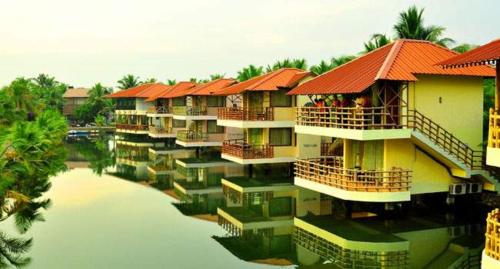 a row of houses with red roofs on the water at Kalathil Lake Resort in Vaikom