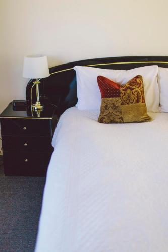 a white bed with pillows and a table with a lamp at Boulevard Motel in Stanthorpe