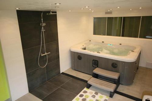 a bathroom with a tub with a shower and a stool at Le Chalet "Les Breuches" in Ramonchamp