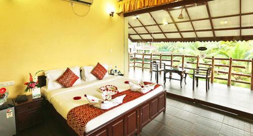 a bedroom with a bed and a balcony with a table at Kalathil Lake Resort in Vaikom