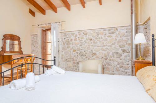 een slaapkamer met een bed en een stenen muur bij Sa Casa Vella in Vilafranca de Bonany