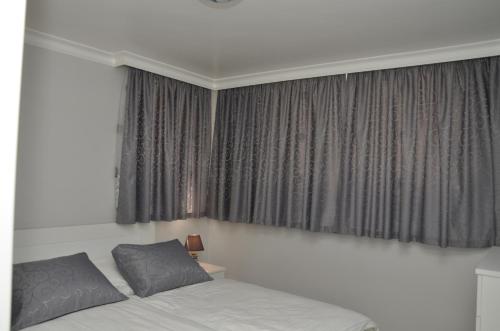 a bed with two pillows in front of a window at Apartments Royal Menex in Požarevac