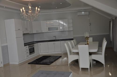 a kitchen with white cabinets and a table and a chandelier at Apartments Royal Menex in Požarevac