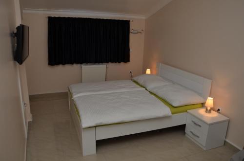 a bedroom with a bed and two lights on a night stand at Apartments Royal Menex in Požarevac
