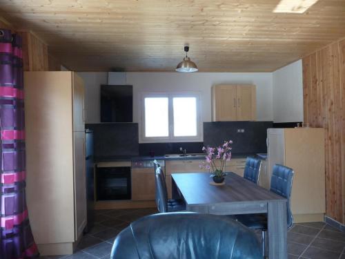 a kitchen with a wooden table and chairs and a table and a kitchen with at Gite chez Jean-Michel in Espinasse
