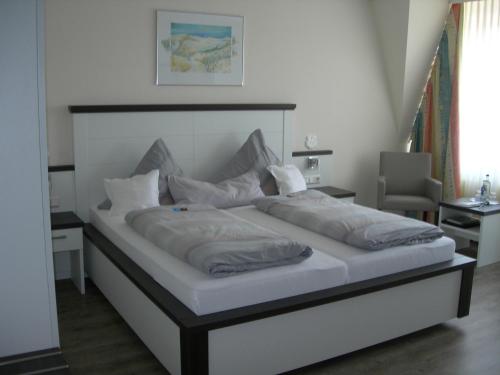 a bedroom with a large bed with white sheets and pillows at Apart Hotel Norden in Norden
