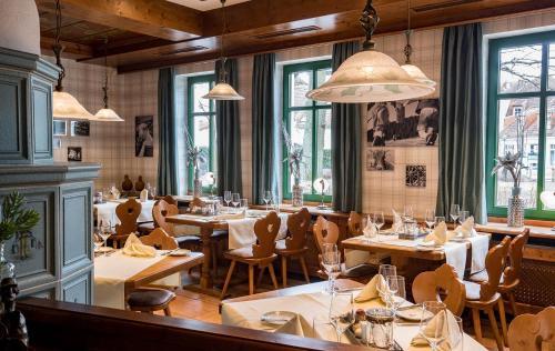 a restaurant with wooden tables and chairs and windows at Landgasthof zum Mühlenteich in Eggersdorf