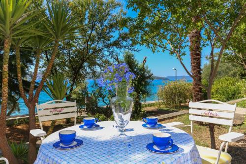 a table with blue cups and a vase with flowers on it at Secret Garden Barada Beach Apartment in Trogir