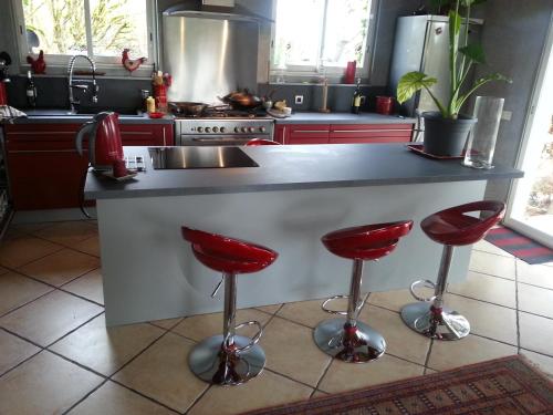 eine Küche mit einer Theke mit roten Barhockern in der Unterkunft Asinus 32 in Viozan