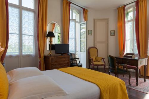 a bedroom with a bed and a desk and windows at La Bellaudiere in Grasse