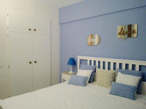 a bedroom with a white bed with blue walls at Summer Home in Armação de Pêra