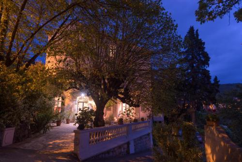a tree in front of a building at night at Logis Hôtel La Bellaudière in Grasse