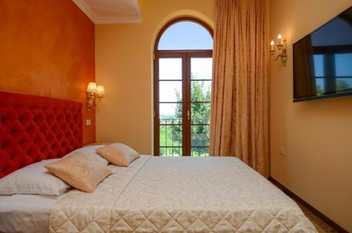 1 dormitorio con 1 cama con cabecero rojo y ventana en Bella & Stella rooms, en Buje