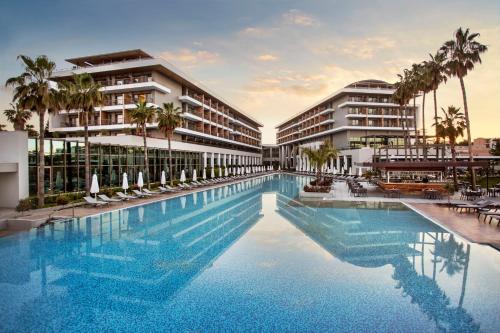 a swimming pool in front of a building with palm trees at Acanthus & Cennet Barut Collection - Ultra All Inclusive in Side