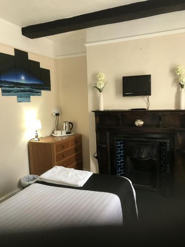a bedroom with a bed and a fireplace at The Black Swan Inn in Leominster