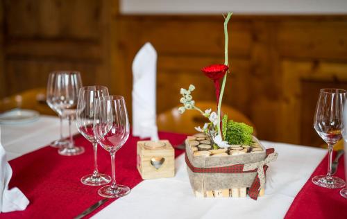a table with wine glasses and a flower in a basket at Landgasthof zum Mühlenteich in Eggersdorf