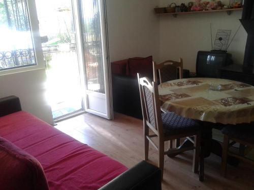 a dining room with a table and chairs and a room with windows at Apartment Pavlovic in Soko Banja