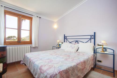 Un dormitorio con una cama azul con dos lámparas y una ventana en Can Boi Den Cifre, en Pollensa