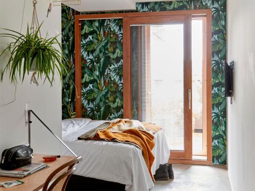 a bedroom with a bed and a desk and a window at Q-Factory Hotel in Amsterdam
