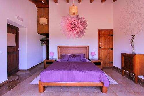 a bedroom with a bed with purple sheets and a flower on the wall at Vida Pura Guesthouse in Odeceixe