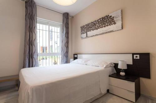 Un dormitorio con una gran cama blanca y una ventana en Triana bridge Apartment, en Sevilla