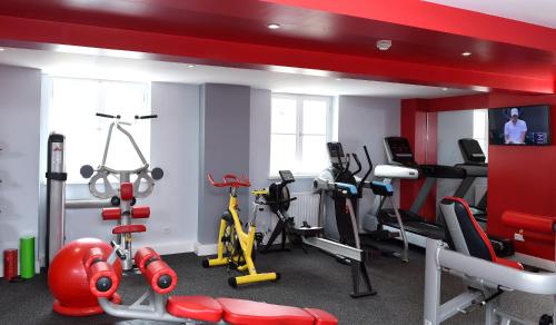 a gym with exercise equipment and a red wall at Gorse Hill Hotel in Woking
