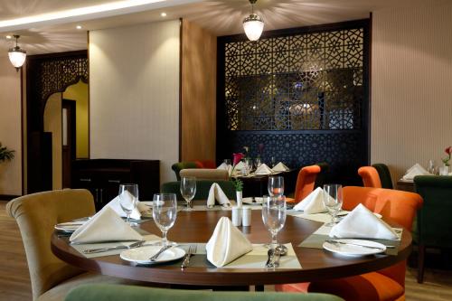 a dining room with a wooden table and chairs at Swiss Flora Inn Hotel Riyadh in Riyadh