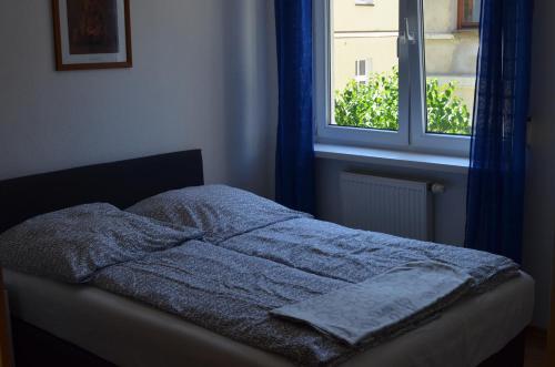 a bed with a blue blanket and a window at Apartament Irek 1000L PP in Międzyzdroje