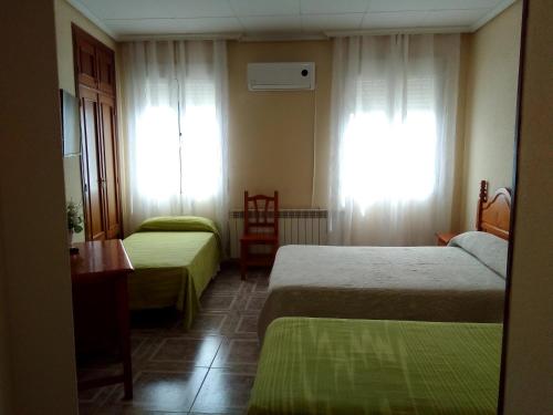 a hotel room with two beds and a window at Hostal Ávila in Ocaña