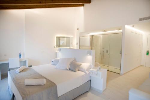 a white bedroom with a large bed and a mirror at Sindic Hotel - Adults Only in Mahón
