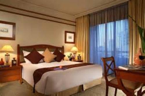 a bedroom with a large bed with a desk and a window at Somerset Grand Citra Jakarta in Jakarta