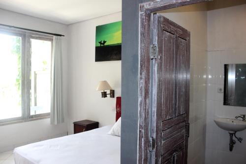 a bedroom with a wooden door and a sink at Bingin Inn in Uluwatu