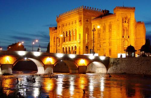 un grand bâtiment avec un pont en face dans l'établissement Guest house Ema, à Sarajevo
