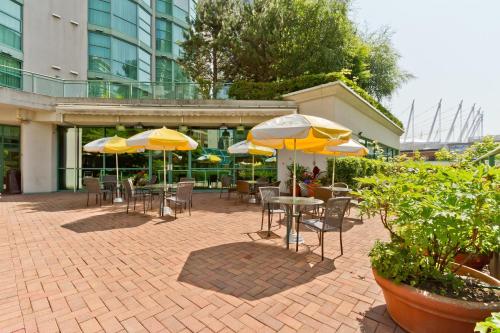 a patio with tables and chairs with yellow umbrellas at Rosedale on Robson Suite Hotel in Vancouver