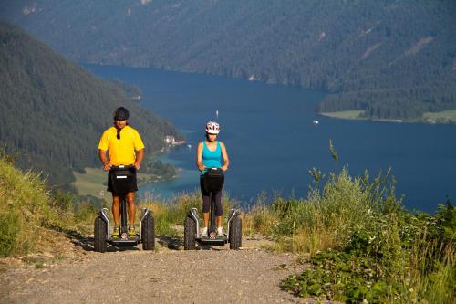 two people riding on segways on a mountain trail at Himmelsbögen und Apartments mit Seeblick und Alleinlage in Weissensee