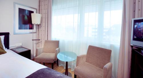 a hotel room with a bed and two chairs and a tv at Home Hotel Aurora in Tromsø