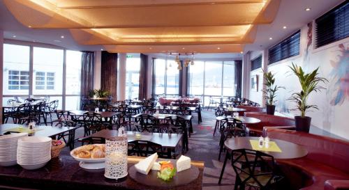 a restaurant with tables and chairs and windows at Home Hotel Aurora in Tromsø
