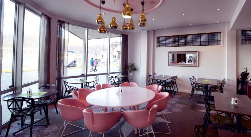 a restaurant with pink chairs and tables and windows at Home Hotel Aurora in Tromsø