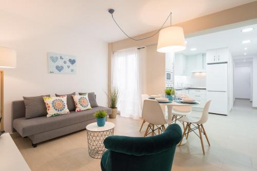 een woonkamer met een bank en een tafel en stoelen bij Peña City Center Apartment in Málaga