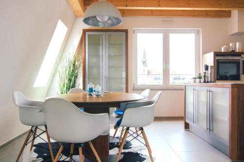 a kitchen with a wooden table and white chairs at Stadtturm Regensburg in Regensburg