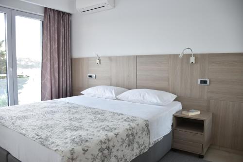 sypialnia z dużym łóżkiem i oknem w obiekcie Beachfront Apartments - Villa Vita w mieście Stara Novalja