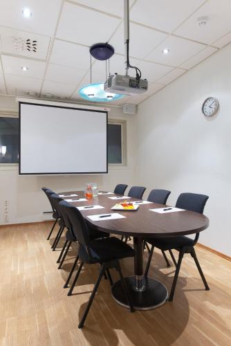 a conference room with a table and chairs and a whiteboard at Home Hotel Aurora in Tromsø