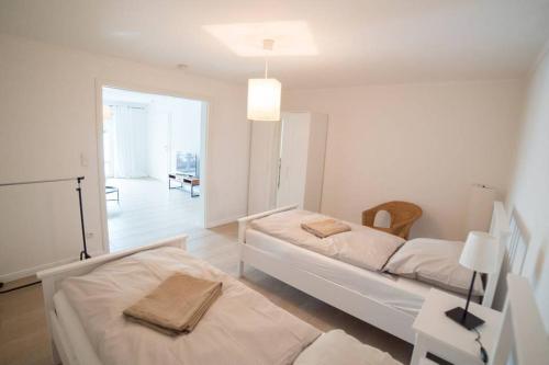 ein weißes Zimmer mit 2 Betten und einem Tisch in der Unterkunft Gästehaus am Paradieshof in Schwerin