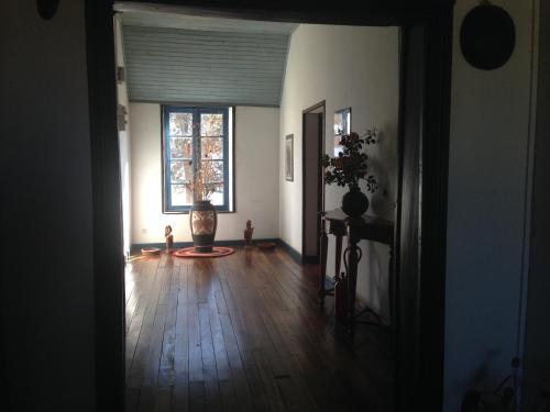 a living room with a wooden floor and a window at Hotel le Trianon in Antsirabe