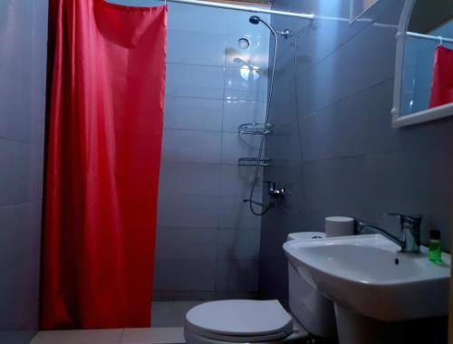a bathroom with a red shower curtain and a toilet at Guest House Villa in Kvareli