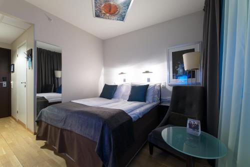 a hotel room with a bed and a glass table at Home Hotel Aurora in Tromsø