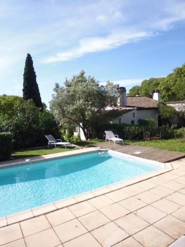 a swimming pool with two chairs and a house at Mas Les Micocouliers in Saint-Christol-lès-Alès
